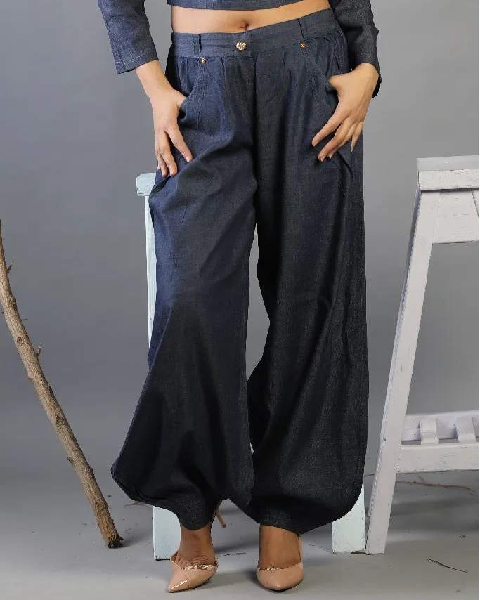 Person wearing dark blue wide-leg pants with a gray background