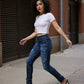 Woman wearing a white crop top and power stretch Element jeans standing on a sidewalk.