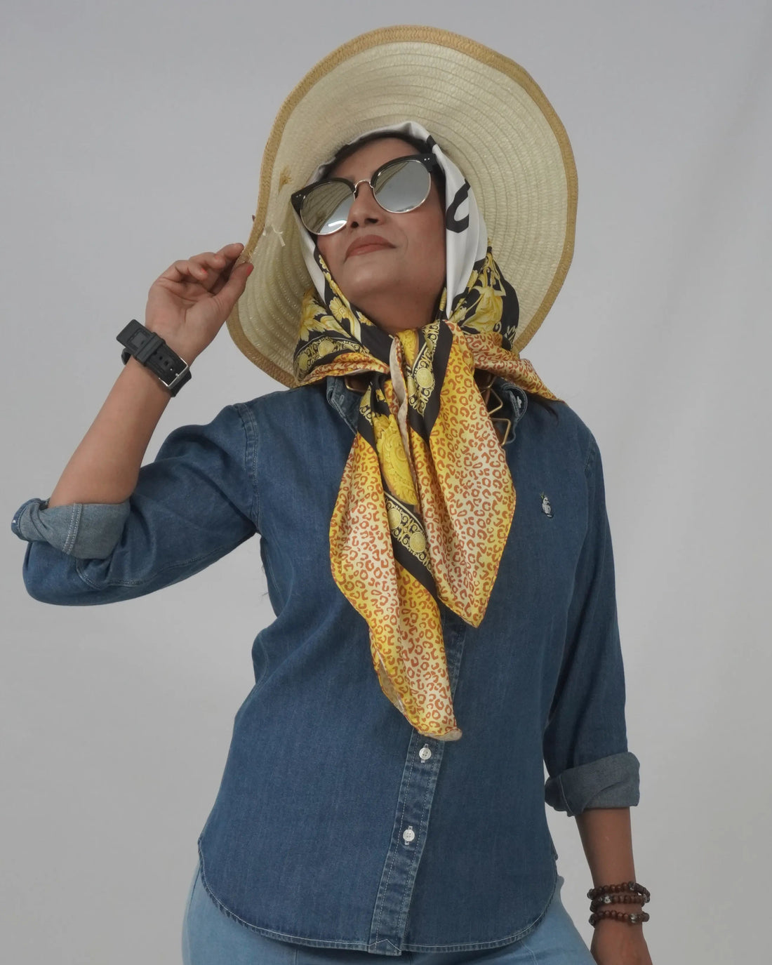 Person wearing a patterned scarf and sunglasses against a plain background