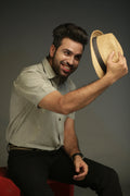Man holding a straw hat against a dark background