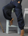 Person wearing dark blue pants sitting on a white stool against a gray background