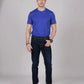 Man wearing a blue t-shirt and dark jeans against a gray background