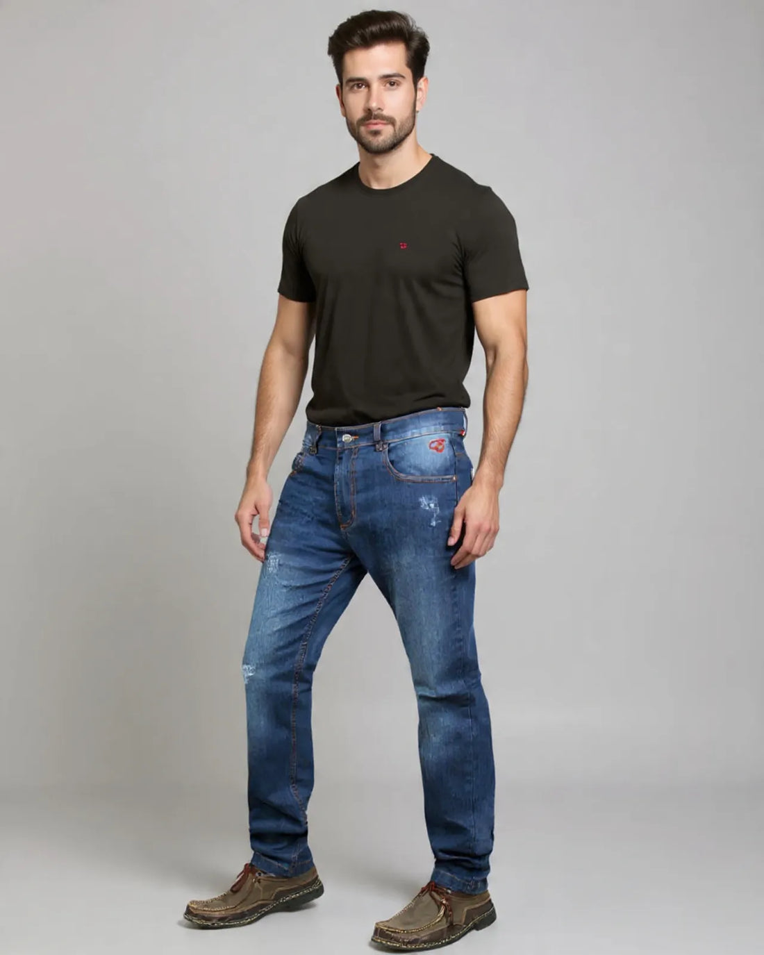 Man wearing a black t-shirt and blue jeans on a gray background