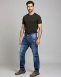 Man wearing a black t-shirt and blue jeans on a gray background