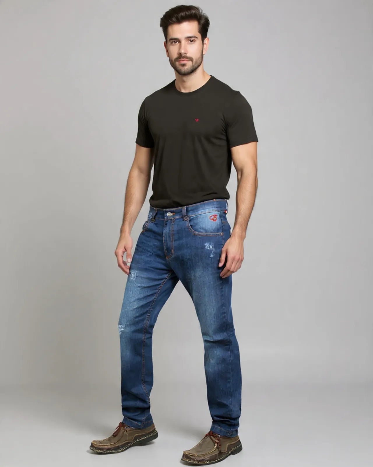 Man wearing a black t-shirt and blue jeans on a gray background
