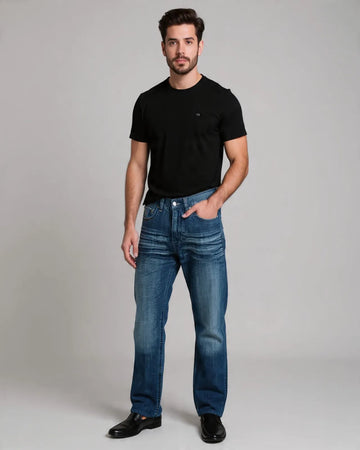 Man wearing a black t-shirt and blue jeans against a gray background