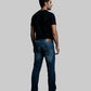 Man wearing blue jeans and a black t-shirt against a dark background