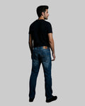 Man wearing blue jeans and a black t-shirt against a dark background