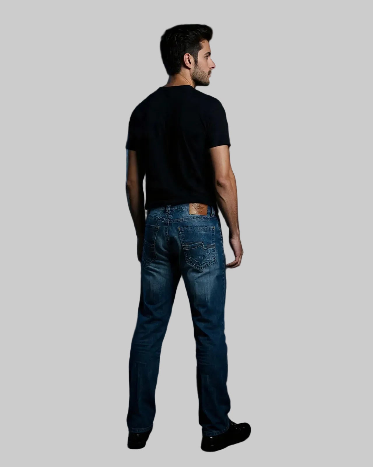 Man wearing blue jeans and a black t-shirt against a dark background