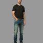 Man wearing a black t-shirt and blue jeans against a gray background