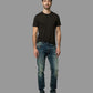 Man wearing a black t-shirt and blue jeans against a gray background