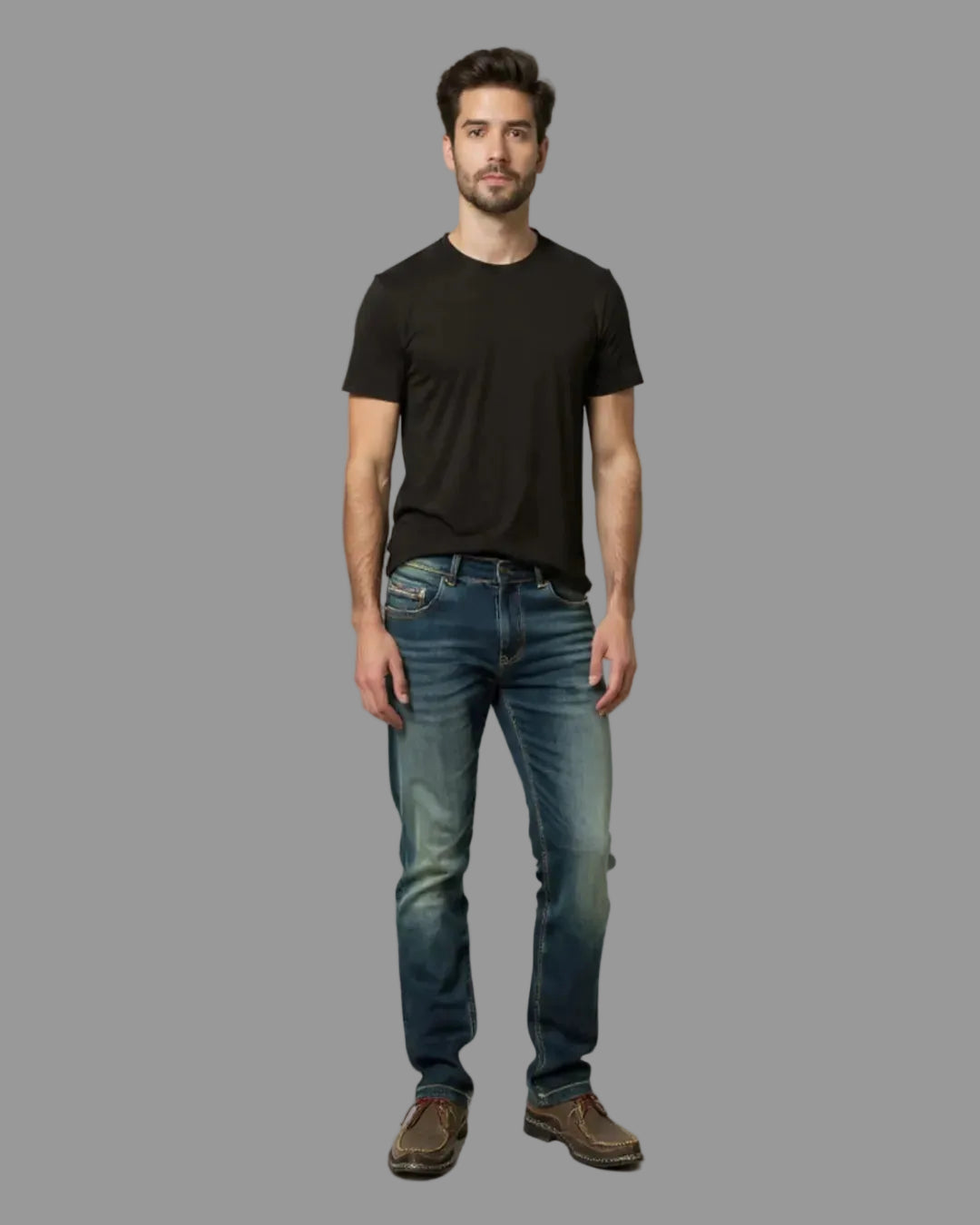 Man wearing a black t-shirt and blue jeans against a gray background