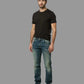 Man wearing a black t-shirt and blue jeans on a gray background