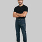 Man wearing a black t-shirt and blue jeans standing against a white background