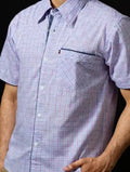Man wearing a short-sleeve checkered shirt against a black background