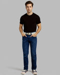 Man wearing a black t-shirt, blue jeans, and white sneakers on a gray background