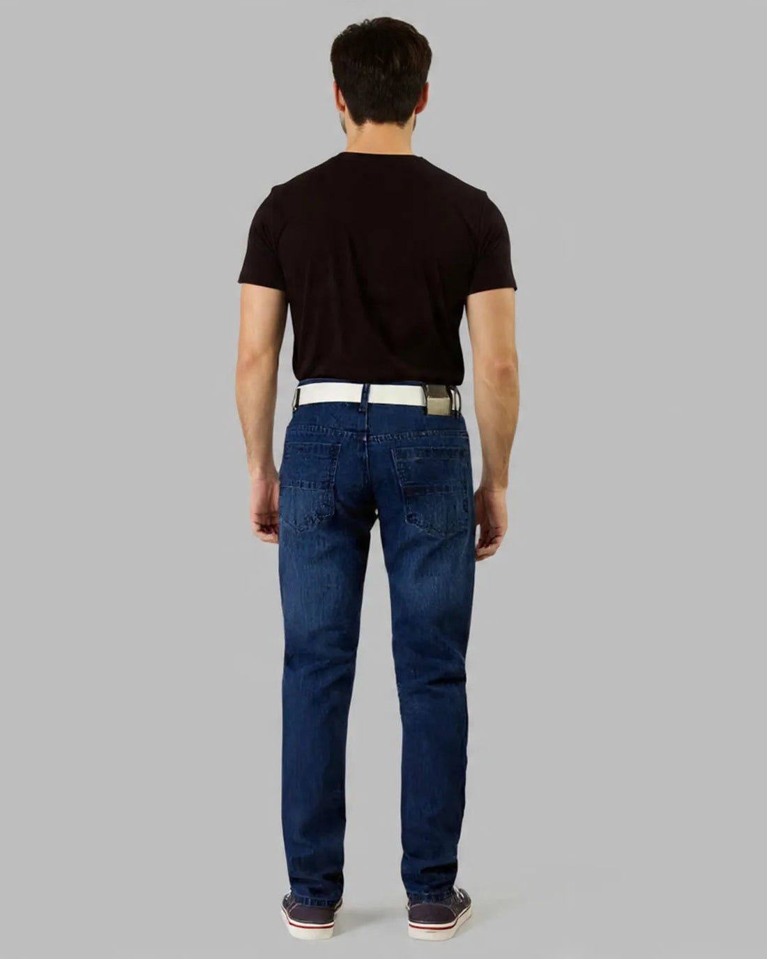 Man wearing a black t-shirt, blue jeans, and white sneakers on a gray background