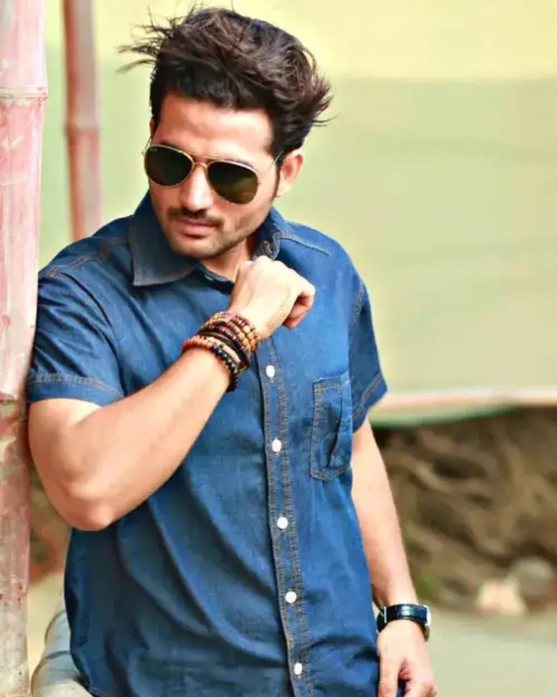 Man wearing sunglasses and a blue shirt with a blurred background