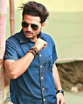Man wearing sunglasses and a blue shirt with a blurred background