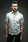 Man wearing a light gray button-up shirt against a dark background