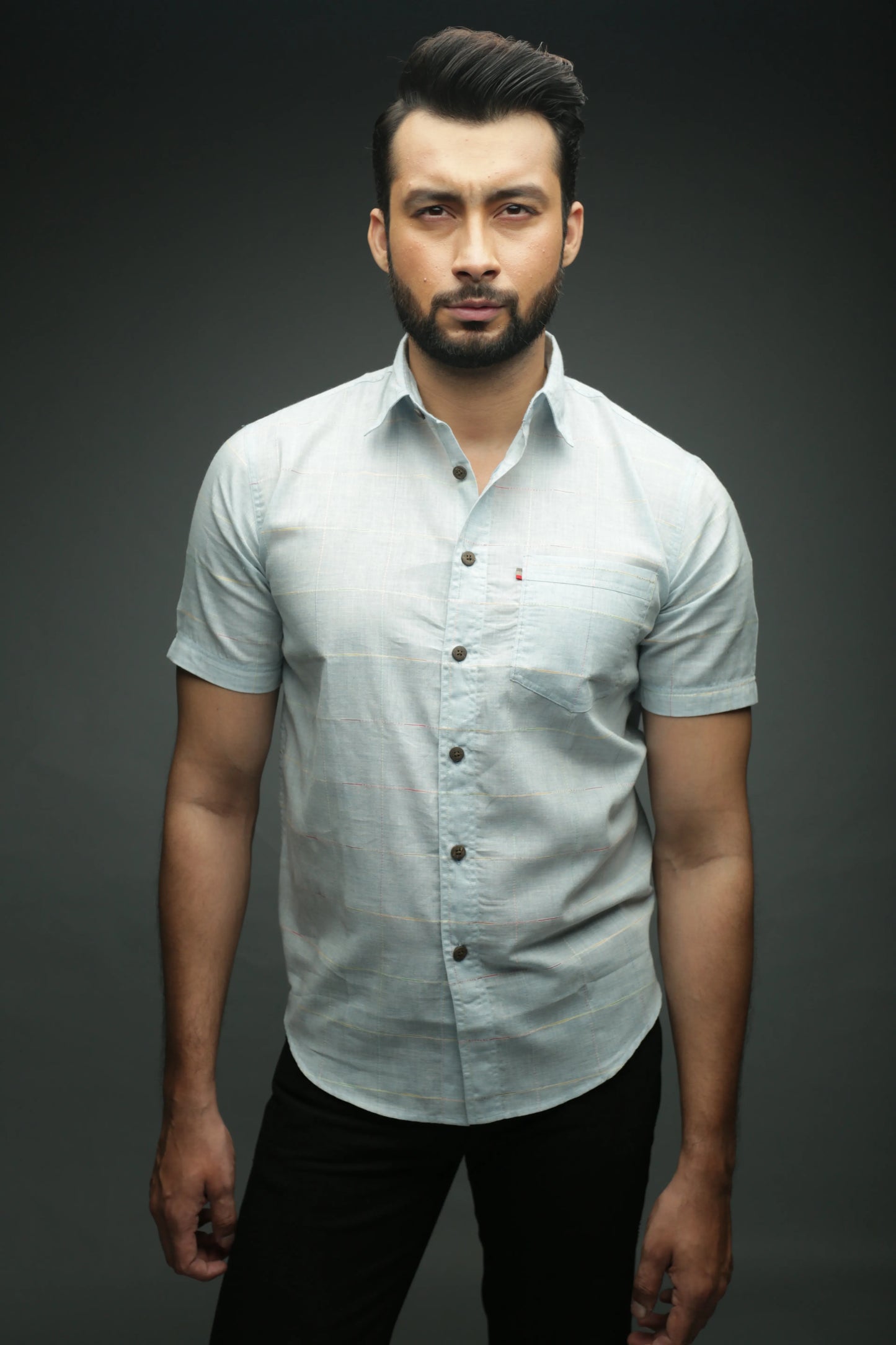 Man wearing a light gray button-up shirt against a dark background