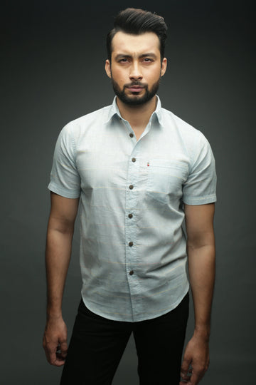 Man wearing a light gray button-up shirt against a dark background
