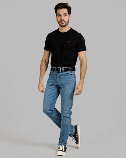 Man wearing a black t-shirt with a red logo and blue jeans on a gray background