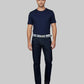 Man wearing a navy t-shirt and dark jeans on a gray background