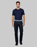 Man wearing a navy t-shirt and dark jeans on a gray background