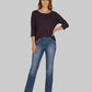 Woman wearing a dark purple sweater and blue jeans on a white background