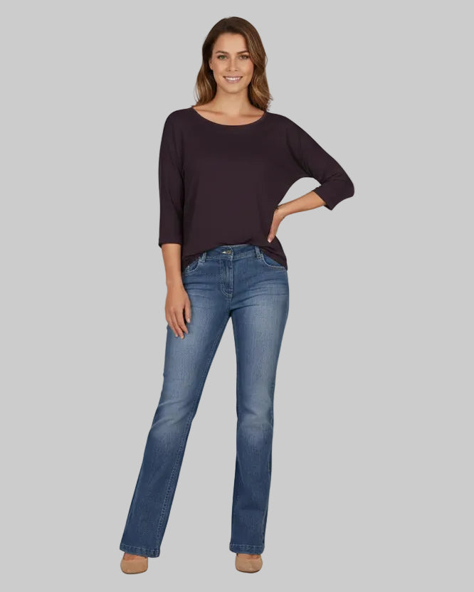 Woman wearing a dark purple sweater and blue jeans on a white background