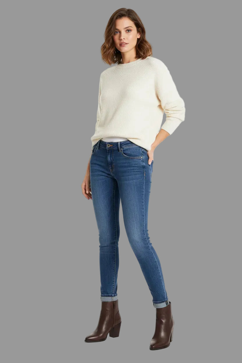Woman wearing a white sweater and blue jeans on a white background