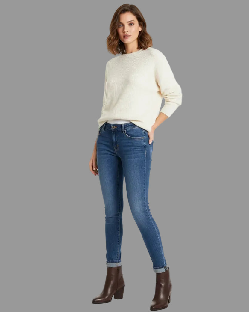 Woman wearing a white sweater and blue jeans on a white background
