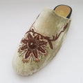 Beige slipper with brown floral embroidery on a light gray background
