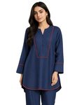 A woman modeling a navy blue two-piece kurta set with red contrast stitching details, standing against a neutral gray studio background.