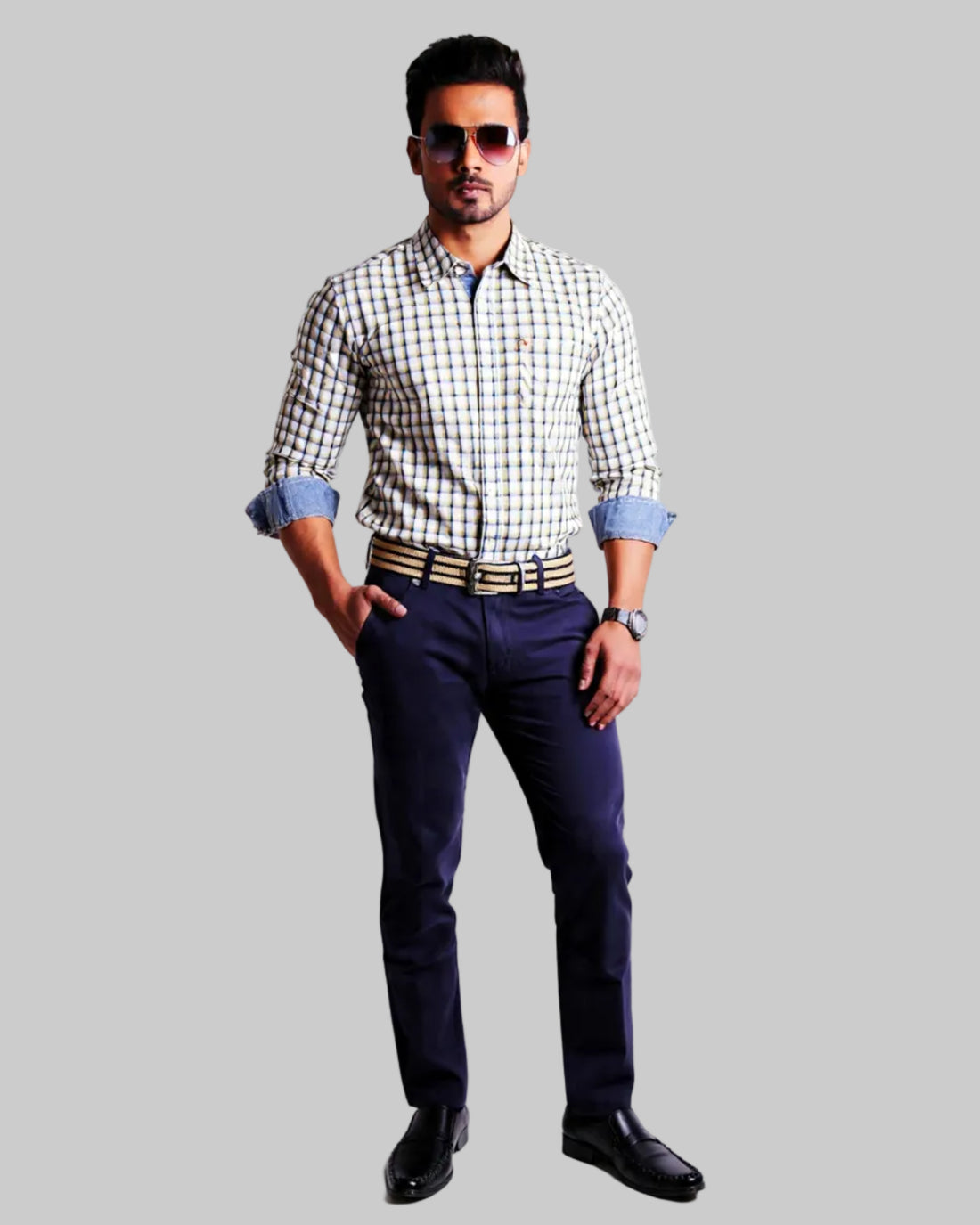 Man wearing a checkered shirt, dark  navy twill pants, and sunglasses on a white background