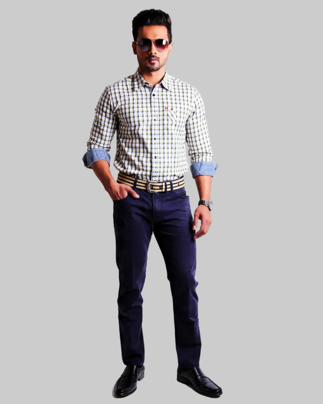 Man wearing a checkered shirt, dark  navy twill pants, and sunglasses on a white background