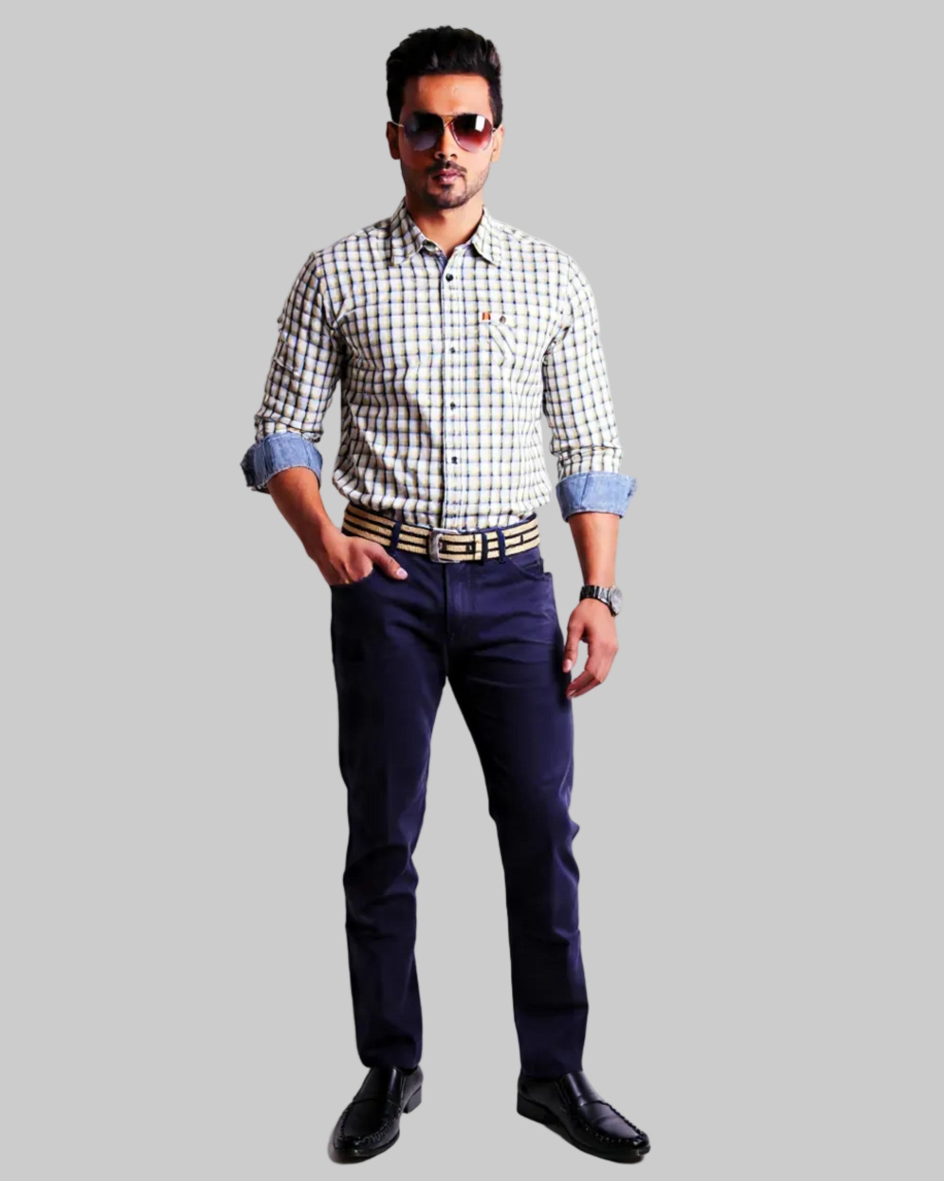 Man wearing a checkered shirt, dark  navy twill pants, and sunglasses on a white background