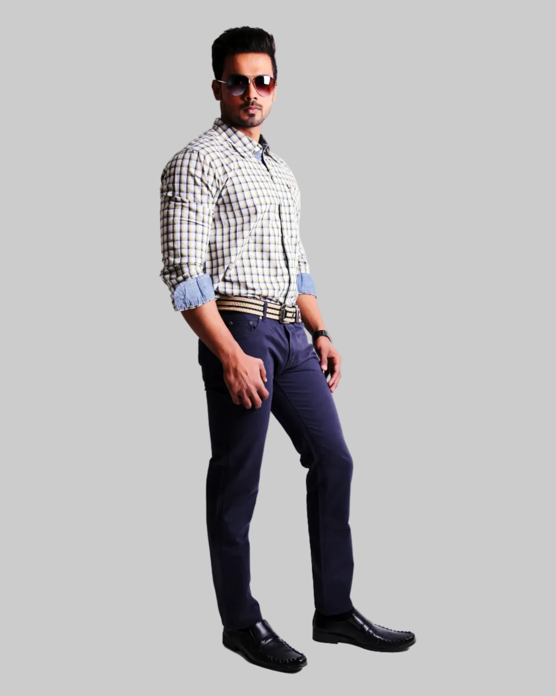 Man wearing a checkered shirt, dark pants, and sunglasses on a white background