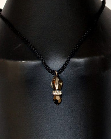 A black leather string neck piece featuring a Swarovski crystal bead and rondell pendant, displayed on a mannequin.