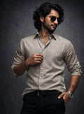 Man wearing a light Olive shirt and sunglasses against a dark background