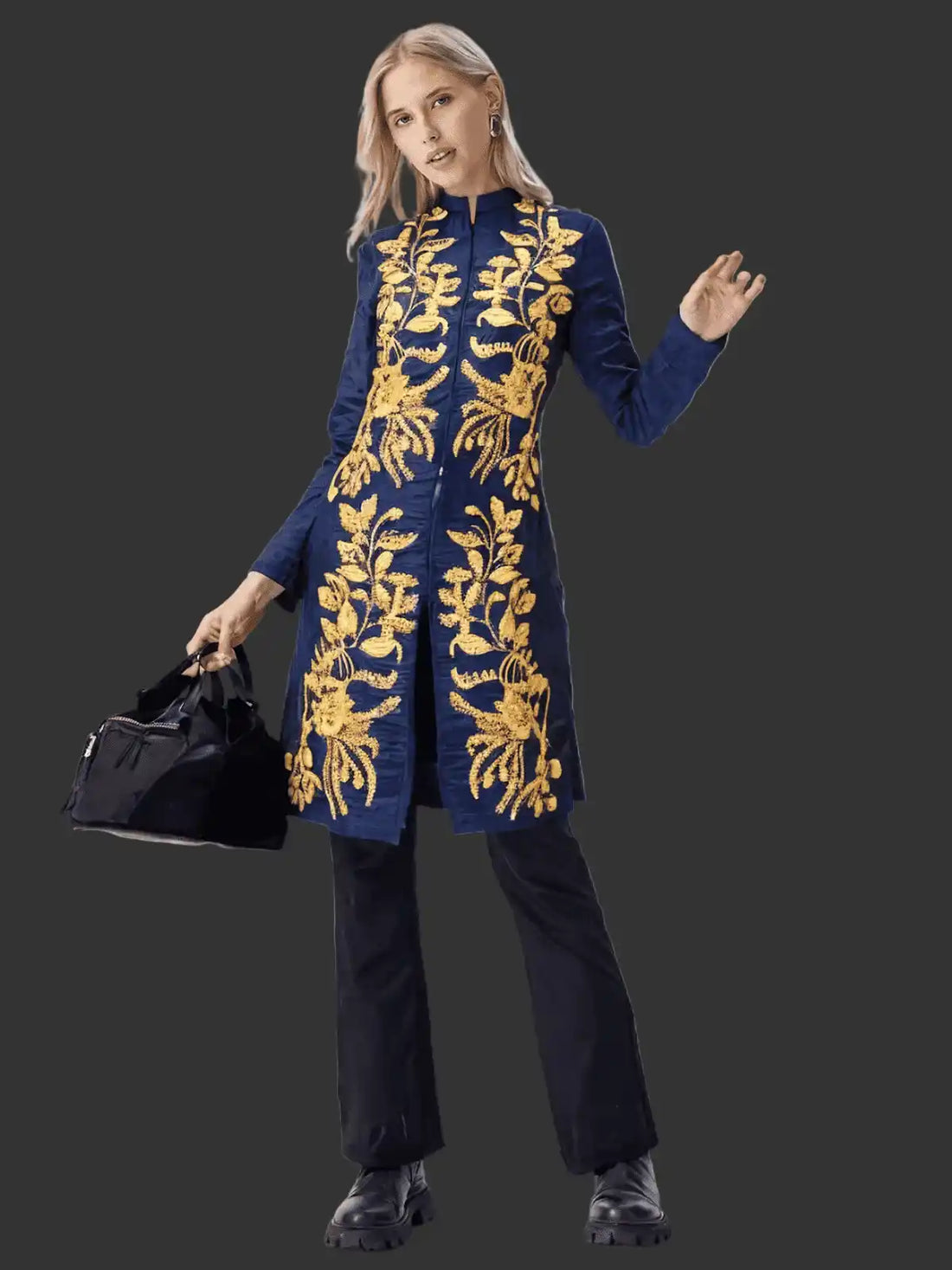 Woman wearing a blue embroidered coat with gold patterns on a black background
