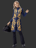 Woman wearing a blue embroidered coat with gold patterns on a black background