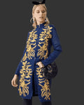 Woman wearing a denim coat with gold embroidery on a dark background