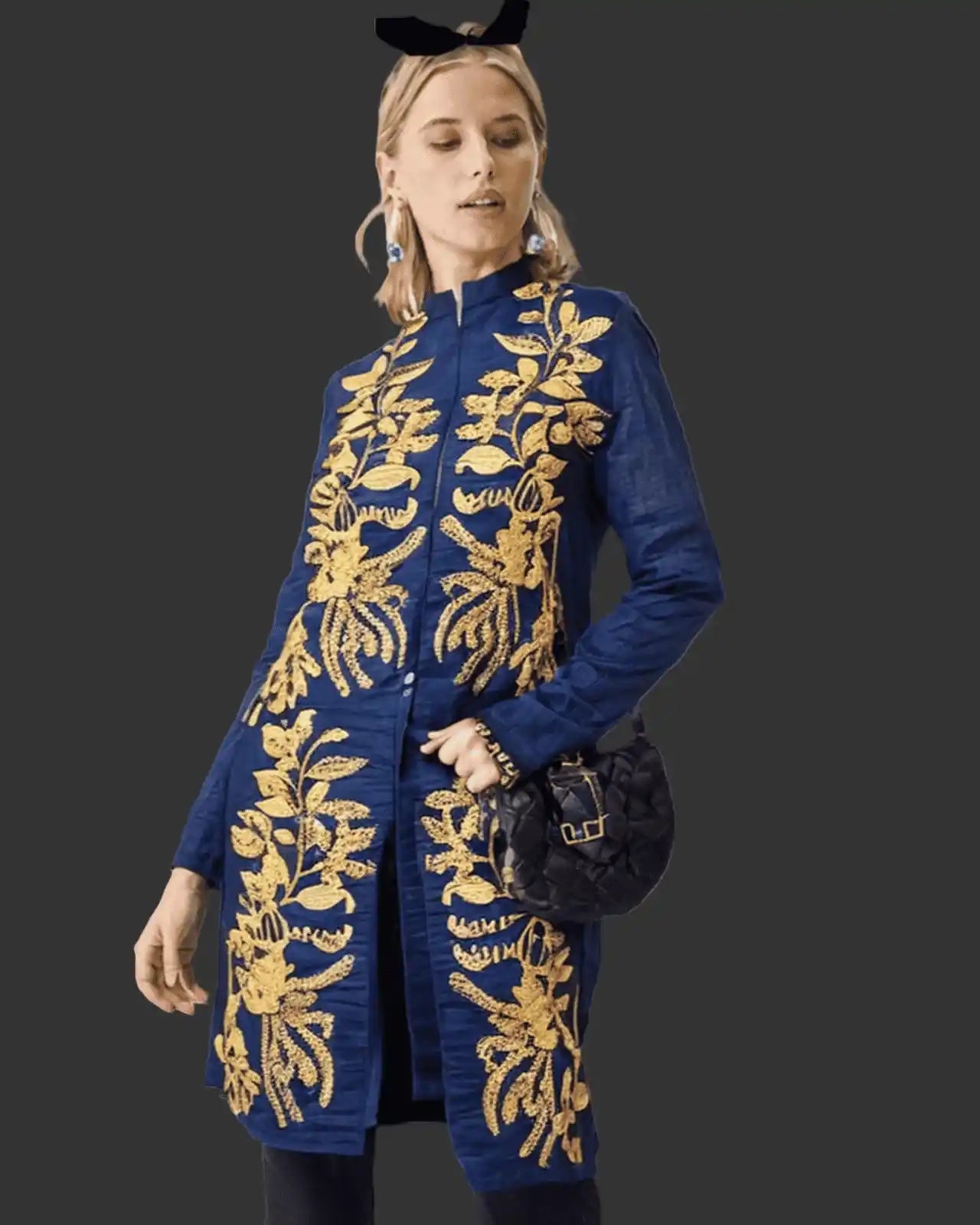 Woman wearing a denim coat with gold embroidery on a dark background