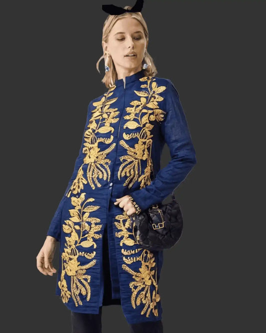 Woman wearing a denim coat with gold embroidery on a dark background