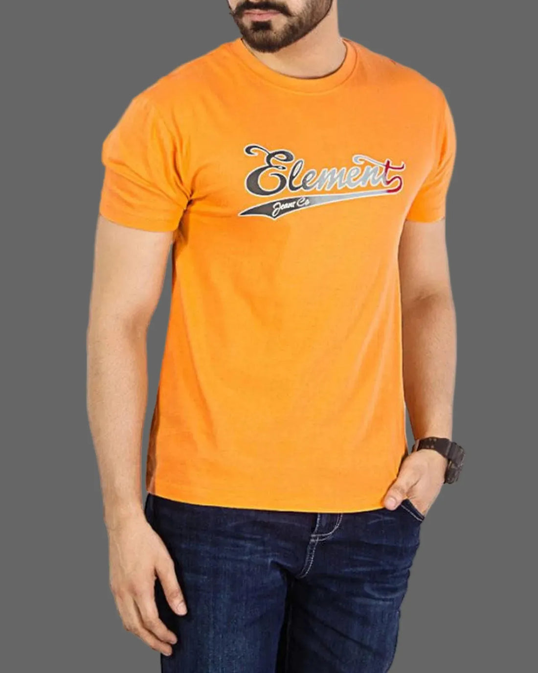 Man wearing an orange t-shirt with a logo and blue jeans on a gray background