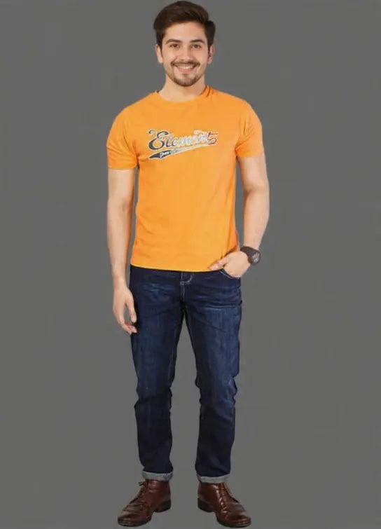 Man wearing an orange t-shirt with a logo and blue jeans on a gray background