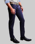 Person wearing navy blue pants and black shoes on a light gray background