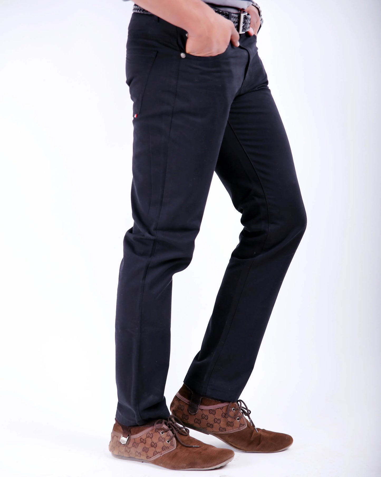 Person wearing black pants and brown shoes on a white background